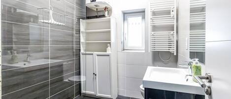 A modern bathroom with a glass shower enclosure, a white vanity with a sink, and a built-in medicine cabinet.