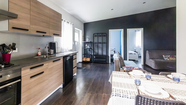 Una cocina moderna con armarios de madera, lavavajillas y comedor con mesa para dos.