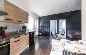 A modern kitchen with wooden cabinets, a dishwasher, and a dining area with a table set for two. - Stunning home in Bouzonville with WiFi (Bouzonville)