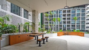 Un área exterior moderna con un bar, asientos y vistas a un rascacielos.