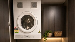 Un lavadero pequeño con lavadora de carga frontal y secadora de carga superior, ambos con etiquetas de eficiencia energética.
