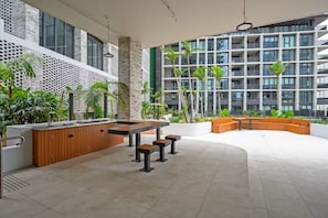 A modern outdoor area with a wooden bar, seating, and planters.