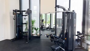 Une salle de sport équipée de matériel de musculation, dotée de grandes fenêtres et offrant une vue sur des vélos d’exercice en plein air.