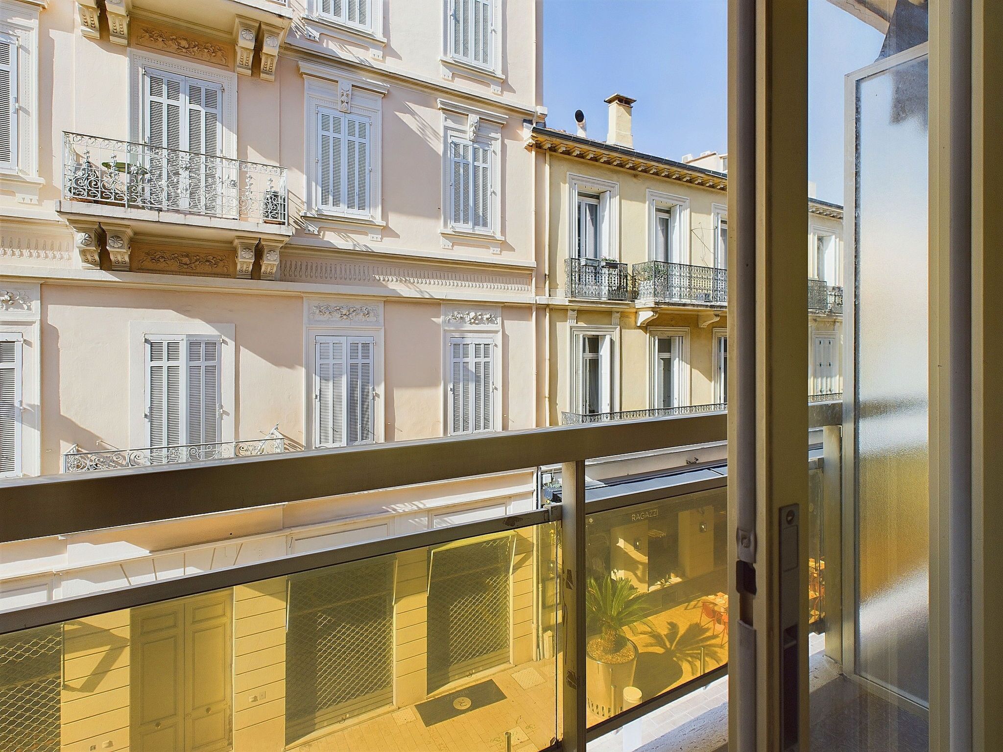 Un edificio de varios pisos con balcones, barandilla metálica y puerta de vidrio.