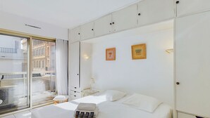 Hotellihuone, jossa on suuri sänky, ikkuna, josta on näkymä rakennuksiin, ja vaatekaappi, jossa on useita lokeroita.