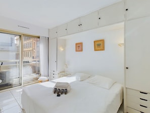 Ein Hotelzimmer mit einem großen Bett, einem Fenster mit Blick auf Gebäude und einem Kleiderschrank mit mehreren Fächern.
