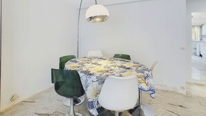 Ruokailutila, jossa on pöytä, tuolit ja riippuvalaisin.