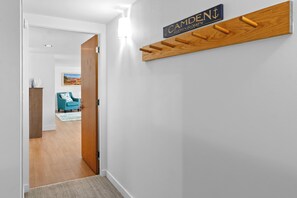 A hallway with a wooden coat rack, a sign reading 'CAMDEN,' and a teal chair in the background.