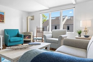 A living room with a fireplace, two armchairs, a sofa, a coffee table, and a lamp.