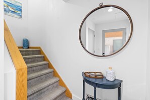 A staircase with wooden handrails, a round mirror on the wall, and a small console table with decorative items.