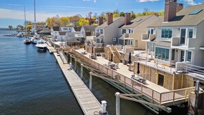 A waterfront property with a dock, boats, and a row of houses.