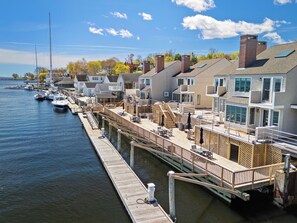 A waterfront property with a dock, boats, and a row of houses.