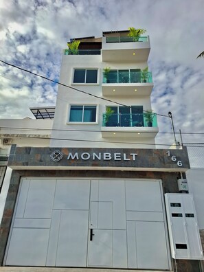 Ein mehrgeschossiges Gebäude mit einer glatten Fassade, einer großen Garagentür und einem Schild mit der Aufschrift 'MONBELT'.