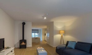 A living room with a fireplace, a sofa, a lamp, and a TV. - Duingolf a by Interhome (Koudekerke)