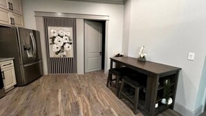 Una cucina con un tavolo di legno scuro, un frigorifero e una porta decorata con motivi floreali.