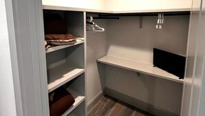 Armadio con ripiani e spazio per appendere, pavimento in legno e una plafoniera incassata.