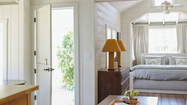 Un'ampia stanza con soffitto in legno, divano, tavolino e lampada.