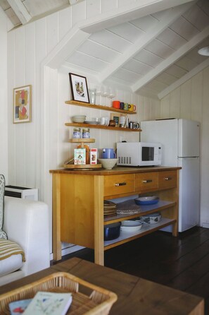 A kitchen with white cabinets, a wooden countertop, a microwave, and a refrigerator.