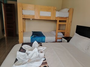 Une chambre avec un lit superposé, une échelle en bois, une couverture bleue et un rouleau de papier toilette sur le lit.