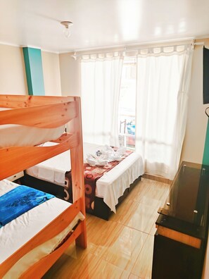 Ein Zimmer mit einem Etagenbett, einem Schreibtisch, einem Stuhl und einem Fernseher.