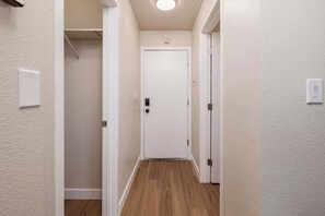 A hallway with a wooden floor, white walls, and a white door at the end.