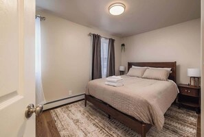 A neatly arranged bedroom with a bed, bedside tables, and a window with curtains.