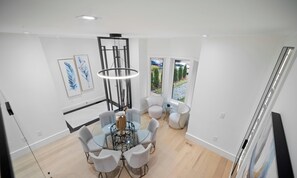 A modern dining area with a glass table, white chairs, and a central light fixture. - Luxury 4BR | High Park, Beach & Lake Views | Toronto (Toronto)