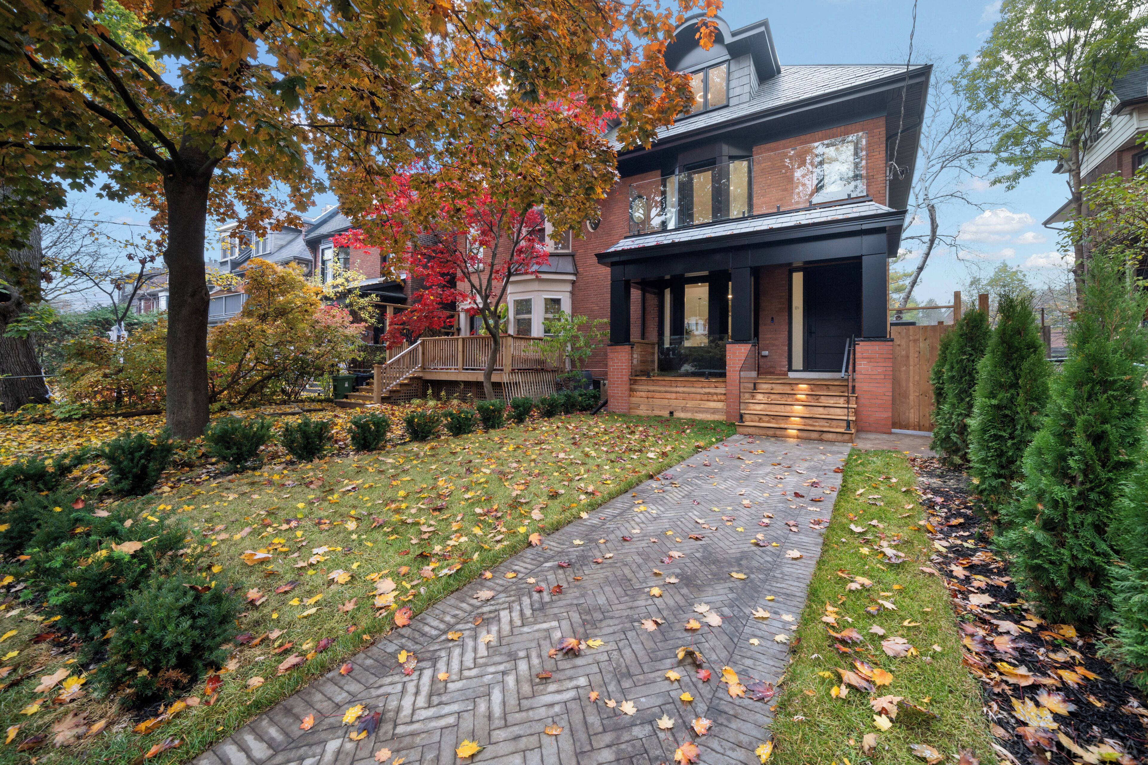 A modern two-story house with a brick exterior, a herringbone-patterned walkway, and a well-maintained lawn.