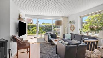 Un salon moderne avec un canapé, des fauteuils, un téléviseur et une cheminée.