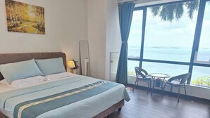 A bedroom with a bed, a window with a view, a chair, and a table.