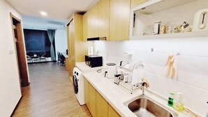 A modern kitchen with wooden cabinets, a stainless steel sink, and a dining area visible in the background.