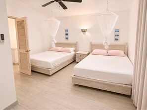 A hotel room with two beds, a ceiling fan, bedside lamps, and a door. - Rare Villa on Jolly Golf Course w/ Plunge Pool (Jolly Harbour)