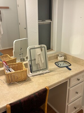 A bathroom with a mirror, a sink, a chair, and a countertop with a basket of toiletries. - Spend a night on a farm. (Scottsdale)