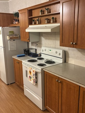 A kitchen with wooden cabinets, a white stove, a toaster, and a refrigerator. - Spend a night on a farm. (Scottsdale)
