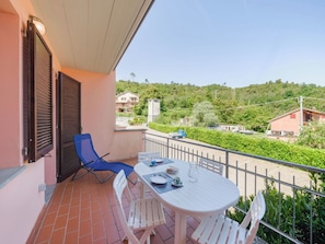 Ein Balkon mit Tisch und Stühlen, ein blauer Stuhl und Blick auf eine Straße und Gebäude.
