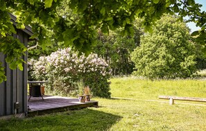A wooden deck with a bench, a small shed, and a flowering bush.