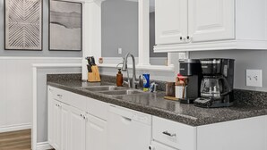 A kitchen with white cabinetry, a granite countertop, a coffee maker, and two framed pictures on the wall. - Serene 4-bedroom house with AC in charming Alhambra (Alhambra)