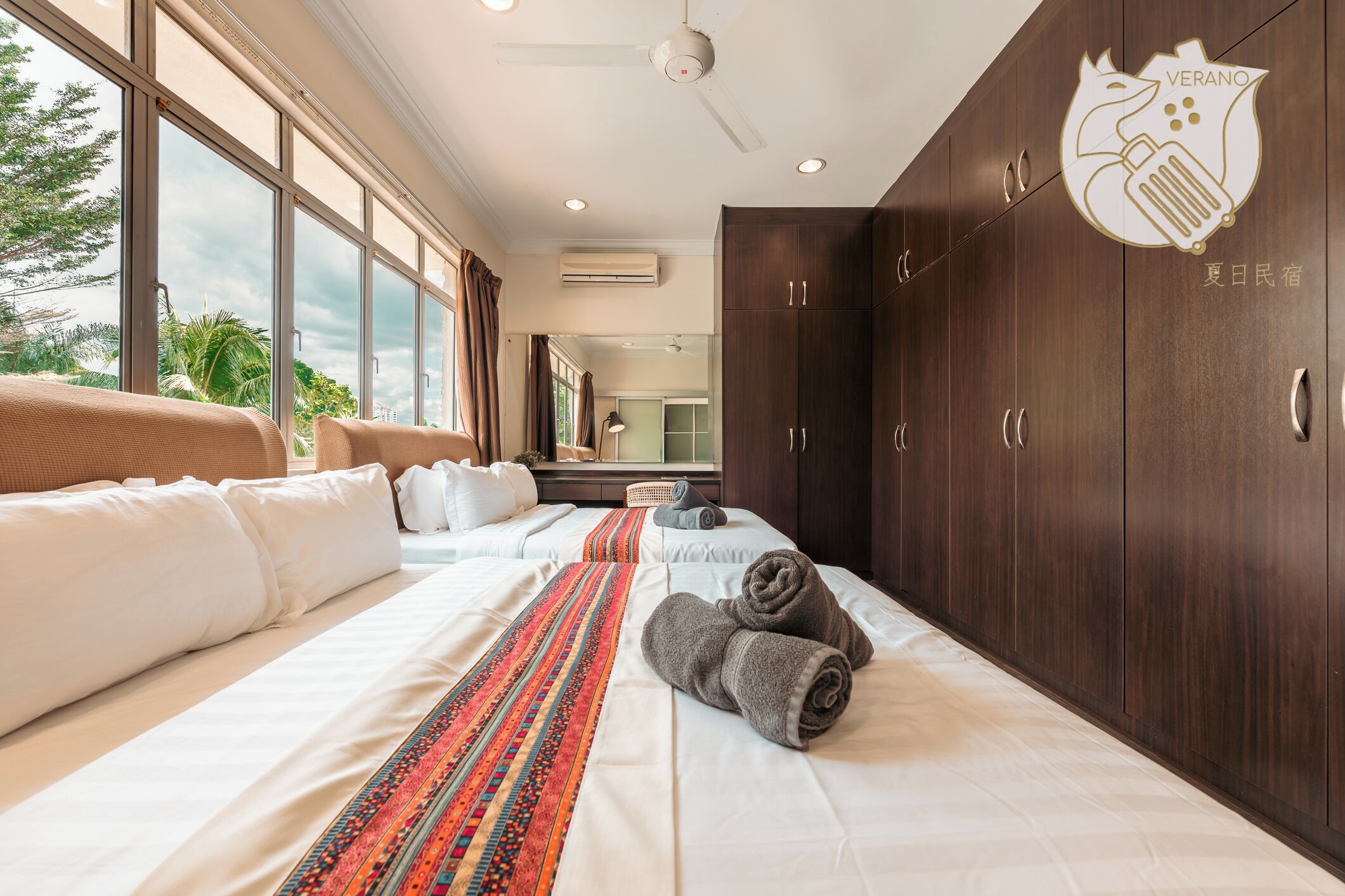 A hotel room with a large bed, a view through the window, and a wardrobe.