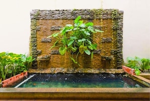 A stone wall with a water feature and plants.