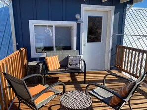 Una terraza con mobiliario exterior, una puerta y una ventana.
