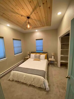 A bedroom with a bed, bedside tables, a ceiling light, and a closet.