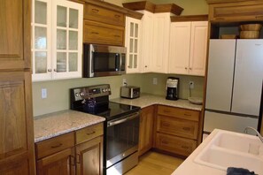 Una cocina con armarios de madera, microondas, estufa, tostadora y refrigerador.