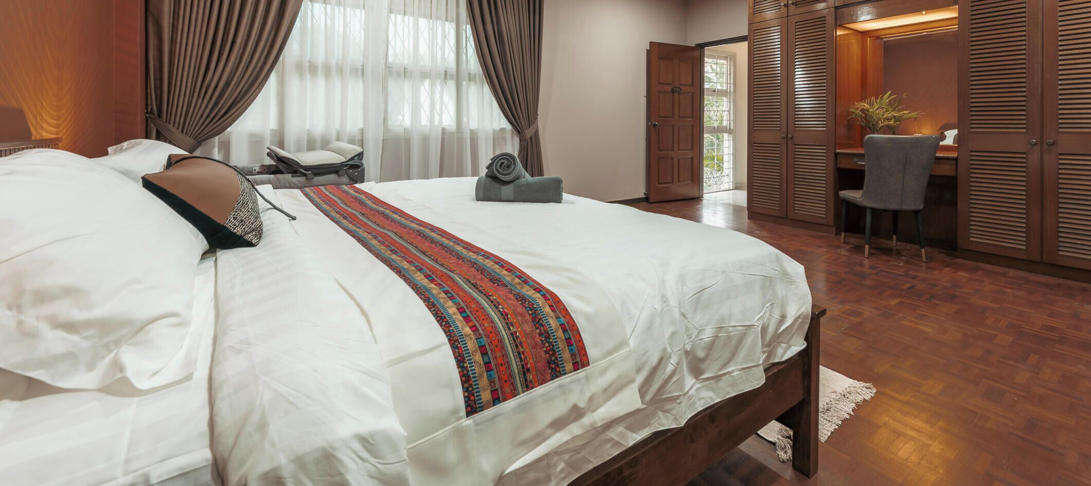 A hotel room with a large bed, a desk, and a wardrobe.