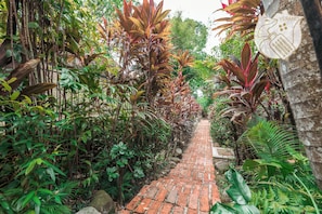 A brick pathway surrounded by lush greenery and plants. - 42Pax 9BR Damansara Pool Villa by Verano (Kuala Lumpur)