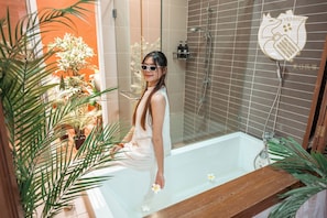 A person in a bathtub with a showerhead, surrounded by plants and a tiled wall. - 42Pax 9BR Damansara Pool Villa by Verano (Kuala Lumpur)