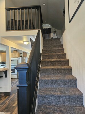A staircase with a dark handrail and carpeted steps leading to a second-floor landing.