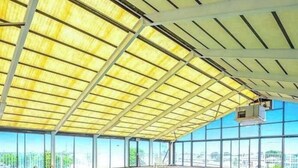 Una piscina interior con techo cubierto, ventanales amplios y vistas a la ciudad.