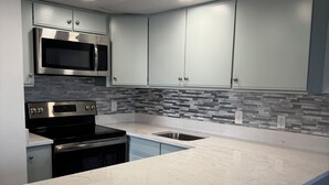 Una cocina moderna con microondas integrado, horno y pileta de acero inoxidable.