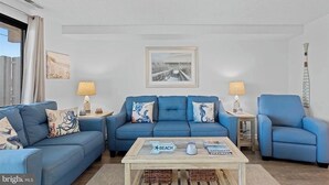 Una sala de estar con dos sofás azules, una mesa de centro y un cuadro en la pared.