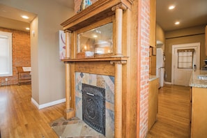 A kitchen with a stone fireplace, wooden cabinets, and a brick wall. - 3 Story Home with Penthouse Suite (Kansas City)